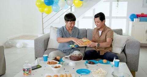 Father and Son Celebrating Birthday with Cake and Snacks at Home