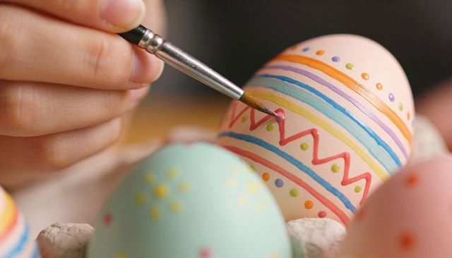 Closeup hand painting pastel easter eggs with colorful stripes dots and glossy finish
