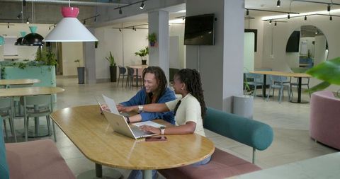 African American coworkers collaborating with laptops, documents in modern coworking lounge