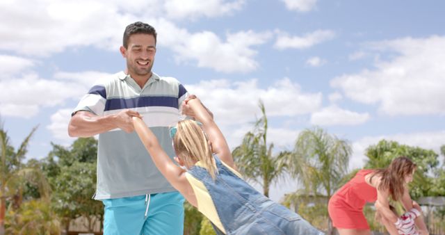 Father and daughter laughing and playing together outside on a bright, sunny day. Perfect for representing family bonding, fatherhood, and joyful outdoor activities. Suitable for advertisements, social media campaigns, and articles about parenting and family life.