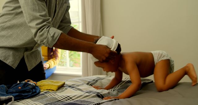 Father Dressing Baby on Bed in Cozy Bedroom - Download Free Stock Images Pikwizard.com