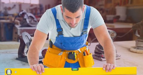 Focused Carpenter Using Spirit Level in Woodworking Workshop - Download Free Stock Images Pikwizard.com