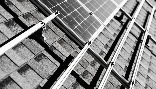 Solar mounting casting long shadows across asphalt shingle roof with aluminum rails