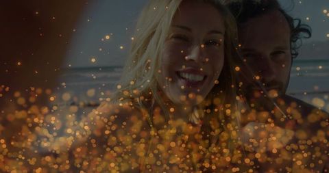 Smiling couple enjoying romantic beach sunset with golden bokeh and ocean horizon