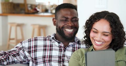 Happy Diverse Couple Relaxing on Couch with Tablet