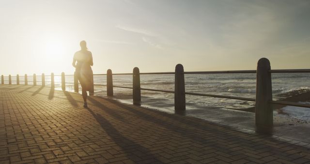 Silhouette of Person Running Along the Ocean at Sunset - Download Free Stock Images Pikwizard.com