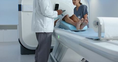 African clinician and nurse preparing male patient for ct scan in hospital radiology room