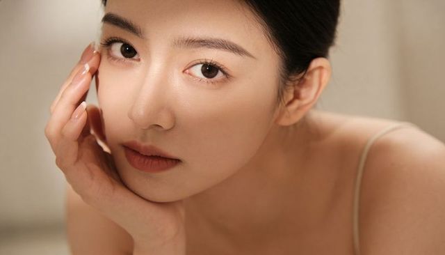Intimate closeup portrait young asian woman with flawless skin, warm soft light, manicure