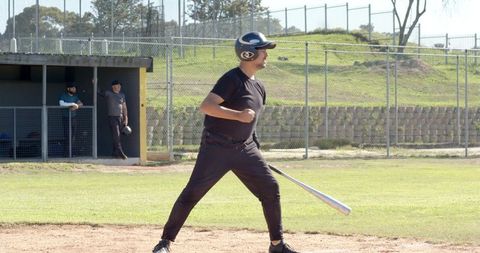 Community Baseball Batter Swinging at Local Diamond with Teammates Watching in Dugout