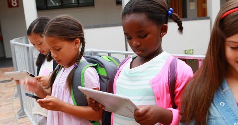 Diverse School Girls Engaging with Gadgets Outdoors - Download Free Stock Images Pikwizard.com