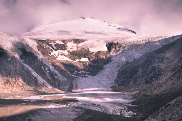 Stunning glacier landscape captured at dawn shows majestic mountains covered in snow and ice. Ideal for use in travel blogs, nature-related content, or environmental conservation campaigns. Evokes a sense of awe and serenity, perfect for inspiring adventure and outdoor exploration.