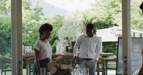 African American Friends Setting Up Elegant Garden Wedding Celebration