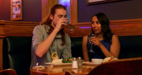 Interracial couple dining in cozy restaurant enjoying drinks