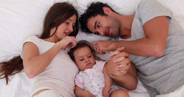 Young parents relaxing with their baby in bed - Download Free Stock Images Pikwizard.com