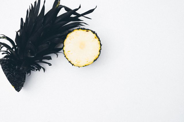 A minimalist shot of half a pineapple on a white background. The fresh, vibrant fruit stands out starkly, making it ideal for use in food and beverage advertisements, healthy lifestyle promotions, or as a modern and stylish artwork piece. Perfect for blogs, websites, and social media posts related to nutrition or tropical themes.