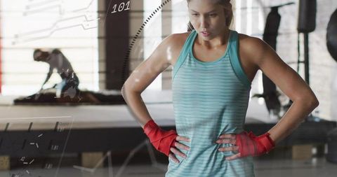 Pausing female boxer catching breath after intense workout in industrial gym