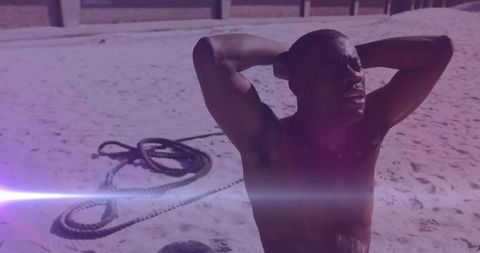 Energetic african american man training on beach with glowing light effect