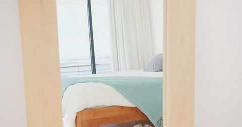 Sunlight in Serene Coastal Bedroom with Ocean View and Wooden Bed