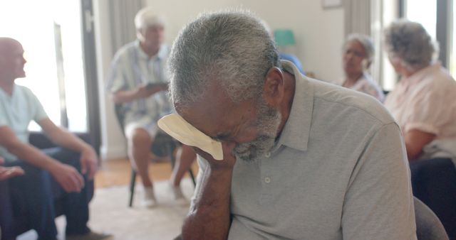 Biracial senior man crying in therapy group. Group therapy, support and mental health awareness, unaltered.