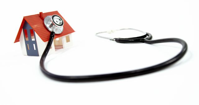 A miniature house is paired with a stethoscope, symbolizing healthcare in the home or real estate appraisal, with copy space. It suggests the concept of a home health check or the importance of health in the housing industry.