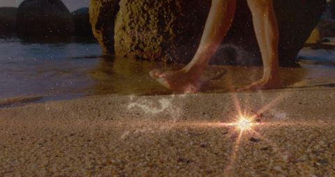 Bare feet on pebbled shoreline with starburst