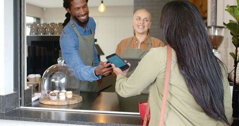 Contactless mobile payment at outdoor cafe window with diverse baristas serving pastries