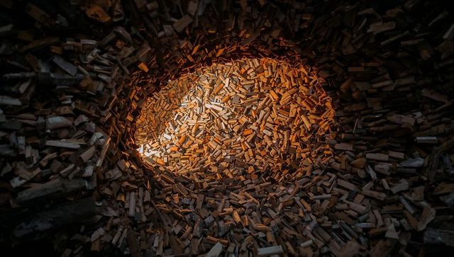 Glowing pile of split firewood forming circular timber nest with warm ambient light