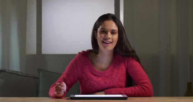 Young woman smiling sitting at desk using tablet during nighttime indoors - Download Free Stock Images Pikwizard.com