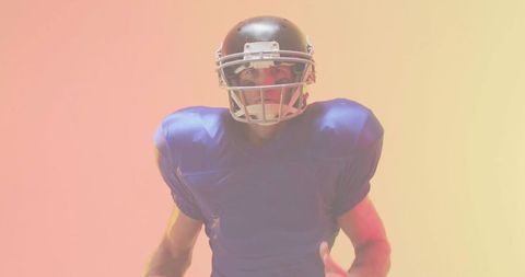 Facing football player wearing helmet and blue shoulder pads on warm gradient background