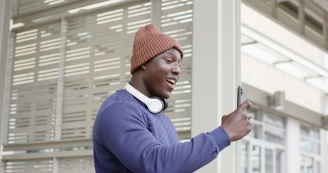 African American Man Making Video Call on Smartphone Wearing Beanie and Headphones