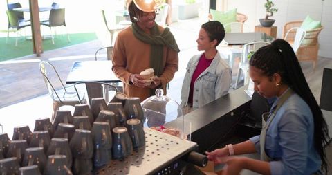 Couple ordering coffee and chatting with barista at sunlit cafe counter