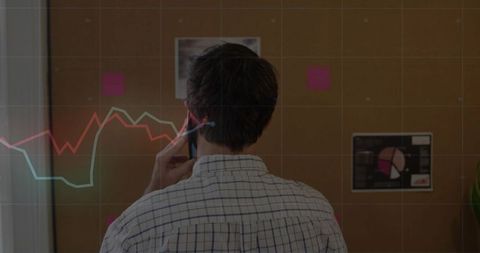 Professional analyzing data on office corkboard with smartphone