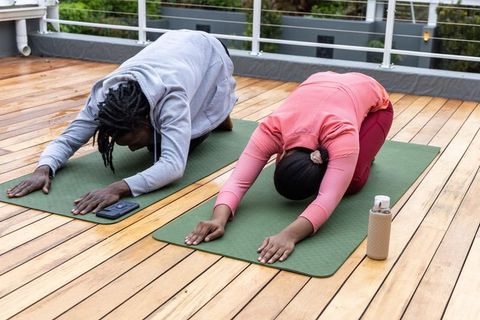 African american couple practicing childs pose yoga on rooftop terrace morning stretch