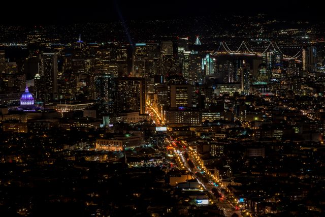 San Francisco's cityscape beautifully lit up at night featuring busy streets and illuminated buildings with iconic bridges in the background. Ideal for promoting tourism, real estate, business travel, or metropolitan lifestyle campaigns.