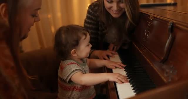 Toddler Exploring Piano with Guiding Adults at Home