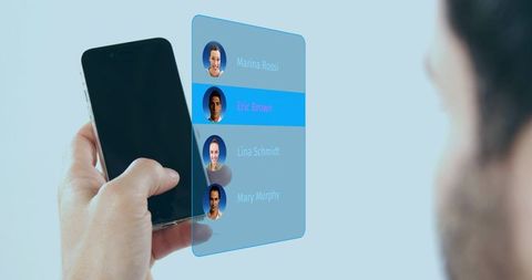 Holding smartphone with holographic contact list selecting contact with blue highlight
