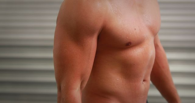 A shirtless young man displays his toned, sweaty body post-exercise against stripes. - Download Free Stock Photos Pikwizard.com