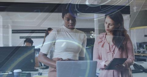 Diverse Female Professionals Using Digital Interfaces in Modern Office