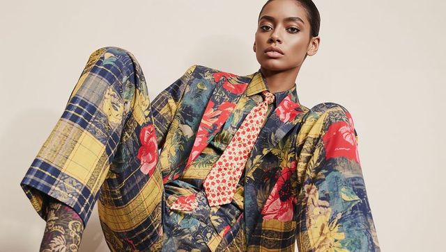 High-fashion model posing in floral-plaid tailored suit with bold red tie, minimalist