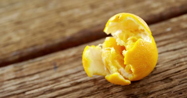 A partially peeled orange rests on a wooden surface, highlighting the freshness and natural aspect of the fruit. Its vibrant color and texture invite a sense of healthy eating and the simplicity of whole foods.
