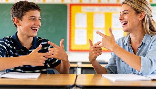 Teacher and student laughing while signing together in classroom for inclusive learning