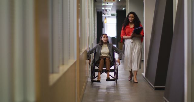 Businesswoman in Wheelchair Discussing Work with Colleague in Office Hallway - Download Free Stock Images Pikwizard.com