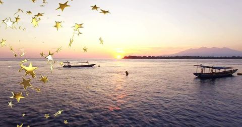 Boat floating on tranquil sunset ocean with golden stars decor