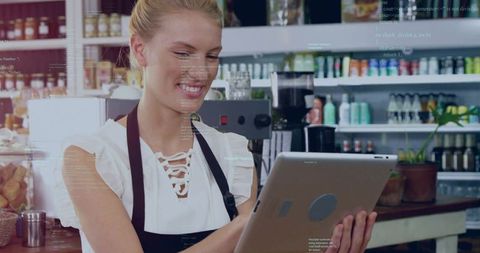 Tapping barista holding tablet behind cafe counter with espresso machine and pastries