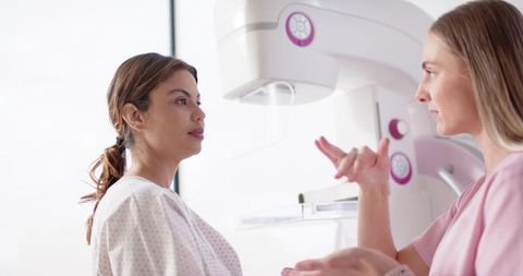 Clinician guiding patient through mammogram exam in radiology clinic for breast screening