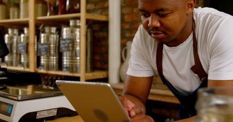 Business Owner Managing Coffee Shop Tasks on Tablet