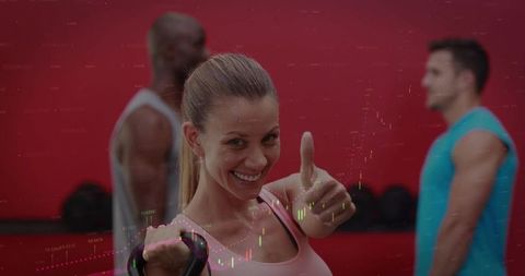 Smiling woman giving thumbs-up during kettlebell workout with group in gym