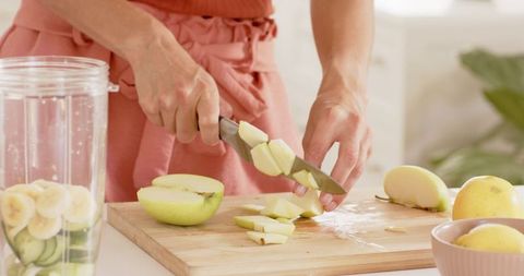 Woman Slicing Green Apple in Modern Kitchen for Fresh Smoothie Prep