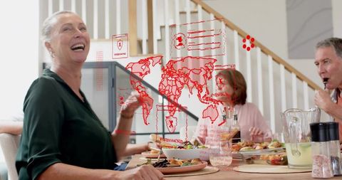 Multigenerational family dining with laughing senior woman and holographic world map