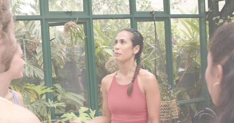 Pacific islander woman leading tropical plant workshop in greenhouse with kokedama